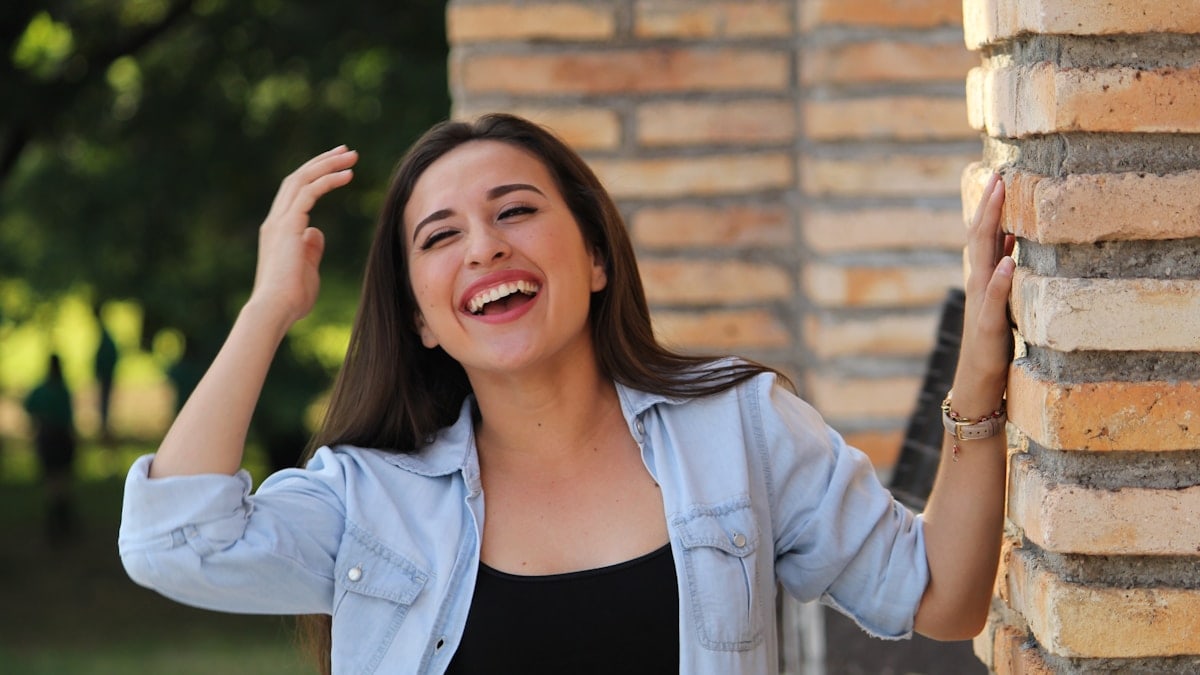 A young woman laughing with her hands in her hair